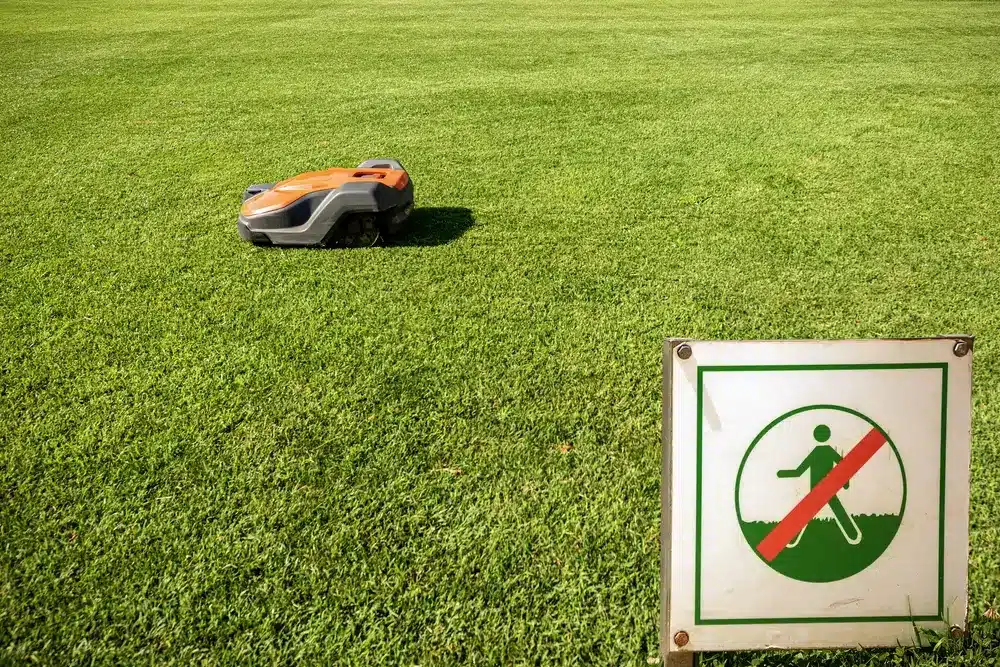 Lawn mower robot working with a keep off the grass sign