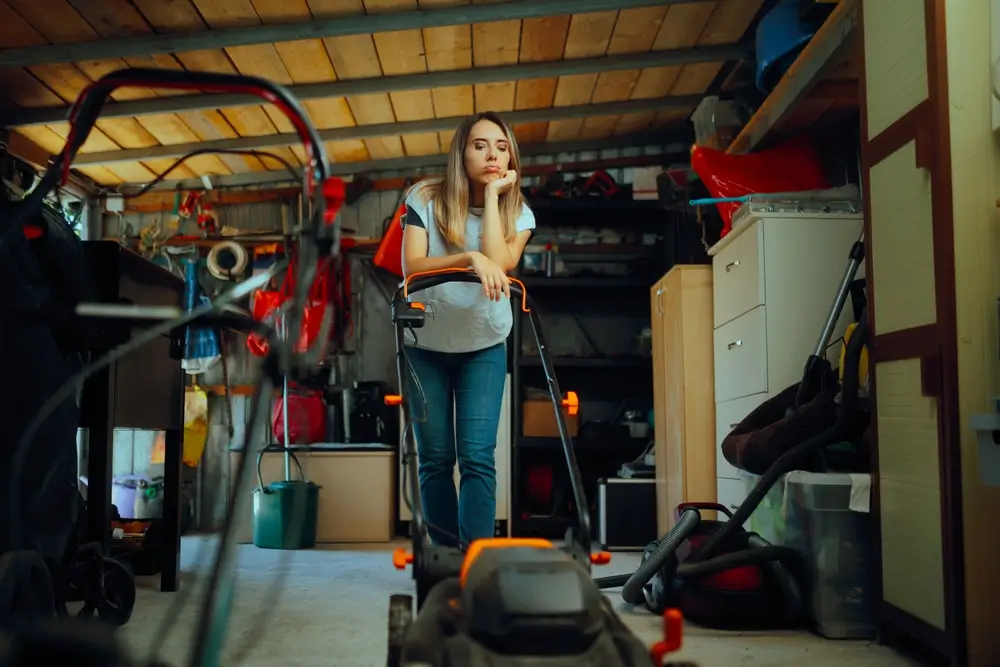 Woman leaning on a lawn mower worrying about her yard